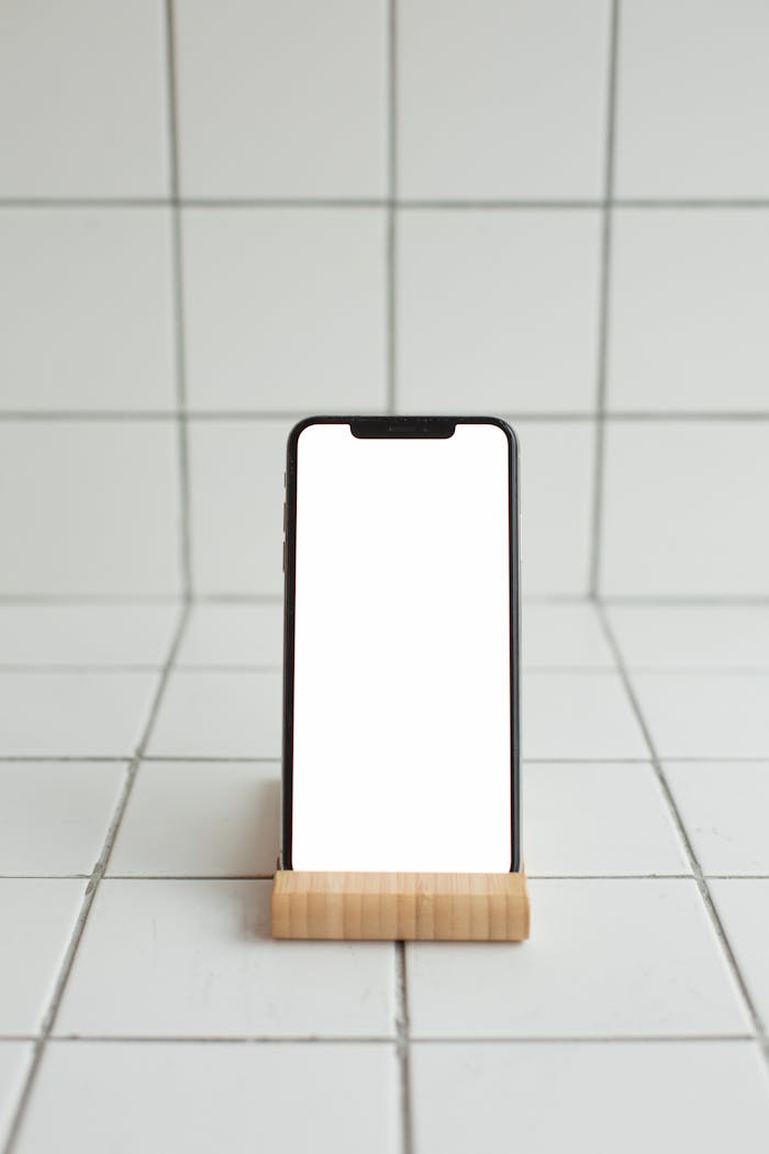 Smartphone with blank screen on a bamboo stand against tile backdrop, ideal for mockups.